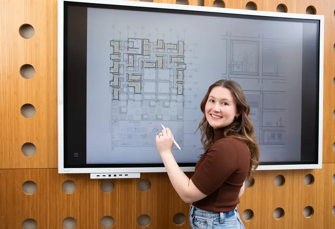 Alumni MaryKate Krege from the school of Architecture sketching on a board.